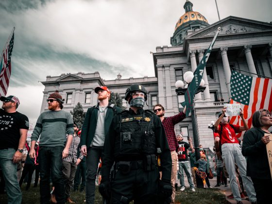 Group of men, including one in black militia uniform protest outside government building in Denver, Colorado
