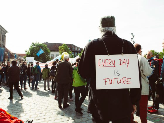 Protester with sign saying "Every day is change" on his back.