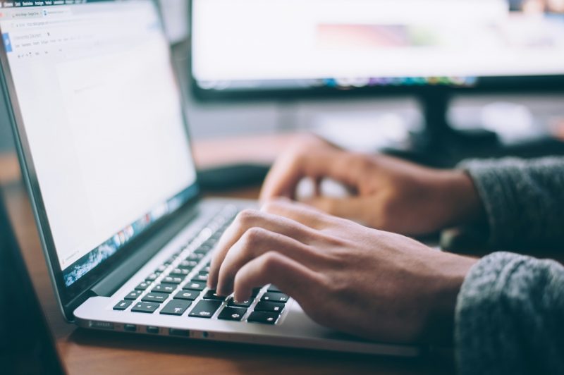 Photo of person's hands typing on laptop