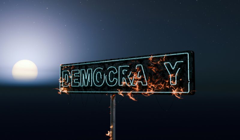 Picture of a burning neon democracy sign